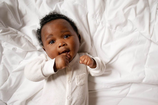 Cute baby laying on their back on a bed.