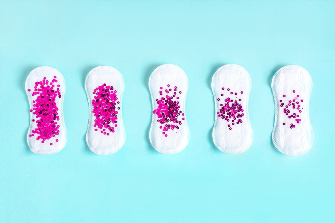 Five sanitary napkins with dark pink glitter on them.
