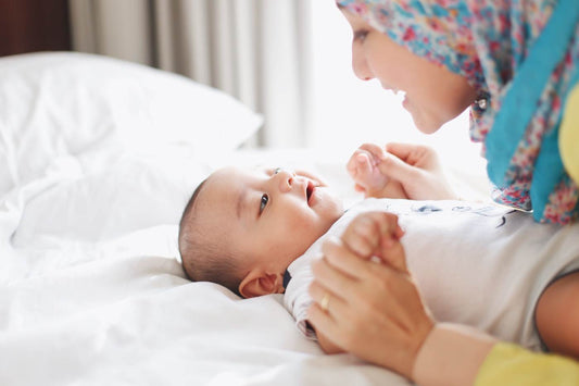 Infant activities - mother playing with young baby on a bed