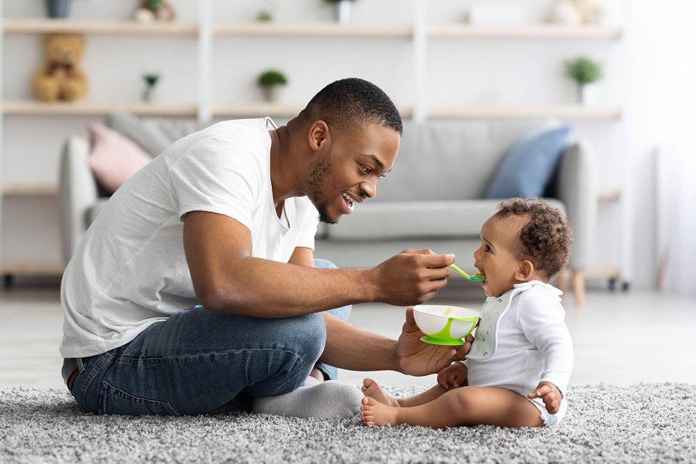 Father feeding baby first purees