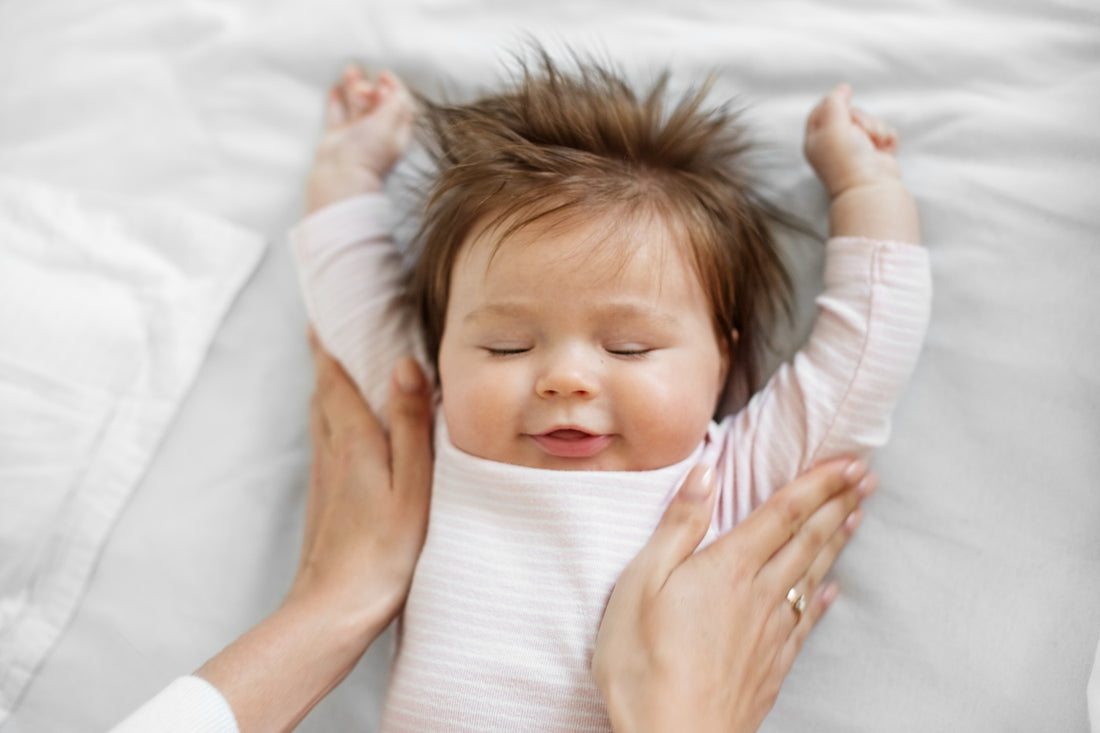 Peaceful baby with arms outstretched overhead