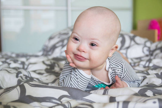 Baby boy laying on his stomach and smiling.