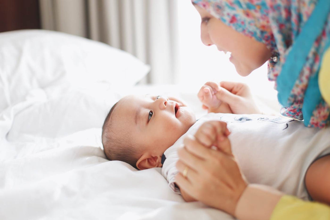 Infant activities - mother playing with young baby on a bed