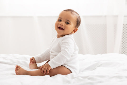 Baby boy sitting on a white bed