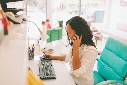 Going back to work after maternity leave - woman on the phone at work while kids play in the background