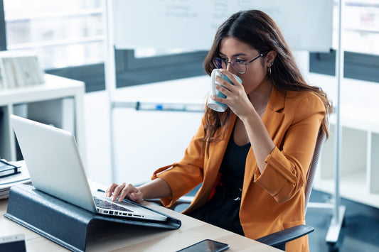 A tired mum drinks coffee at work
