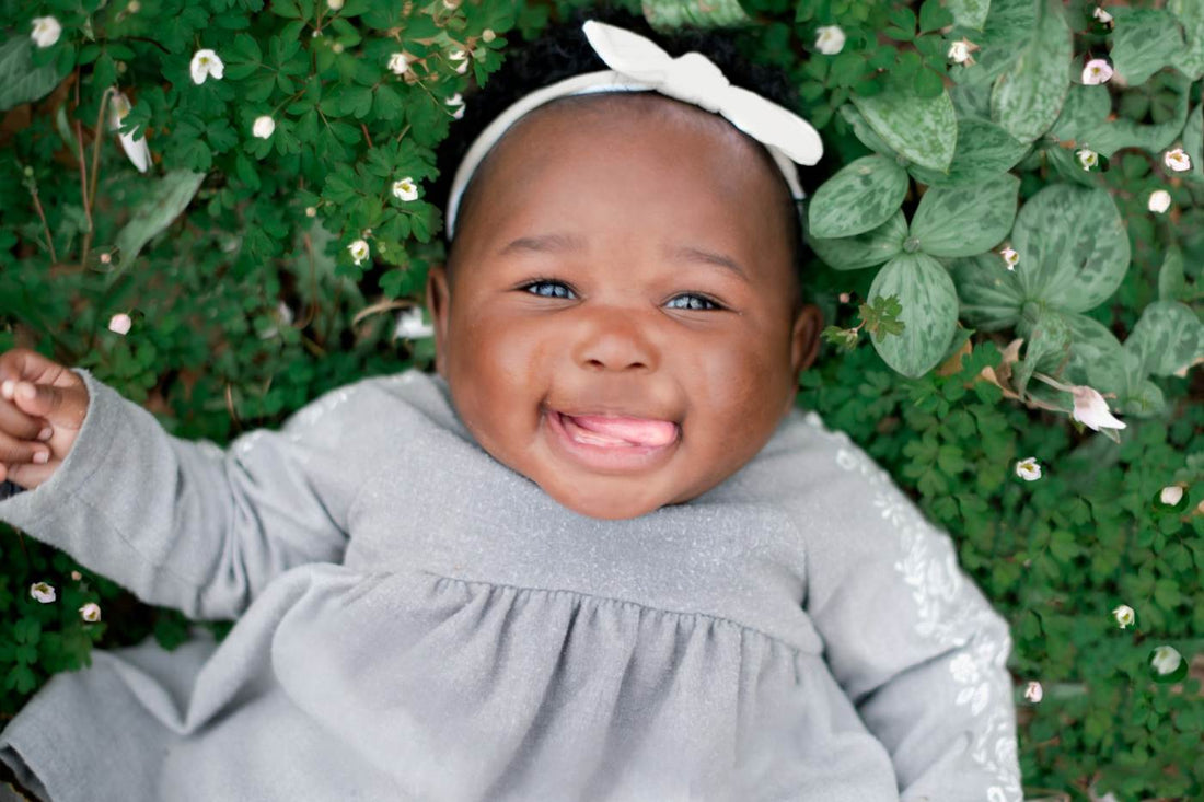 Spring baby names - Baby girl laying in green leaves and white flowers
