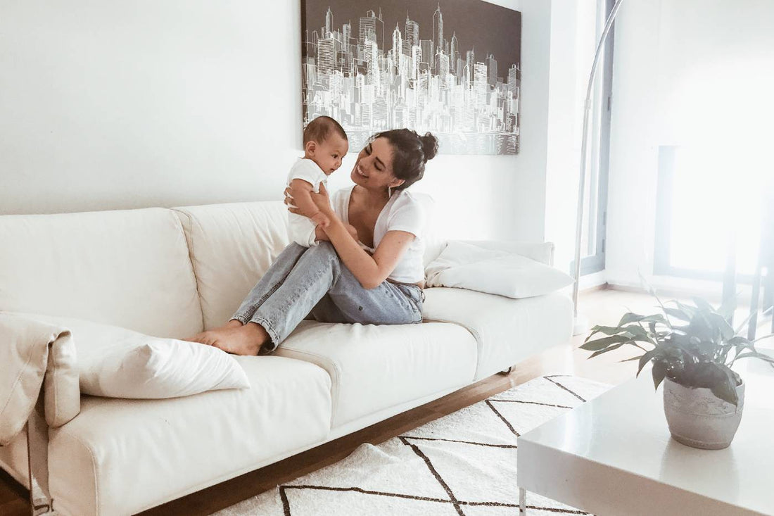 A young woman holds a baby on the couch