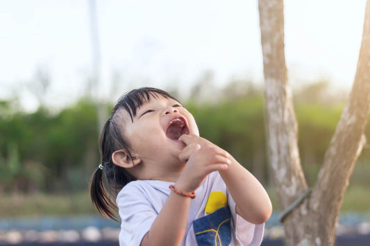 toddler jokes - toddler girl throwing her head back and laughing