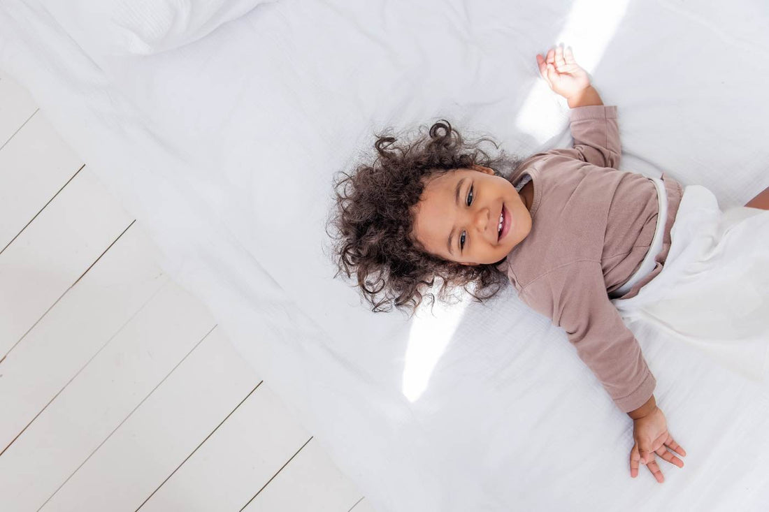 toddler sleep regressions - toddler girl awake and smiling in bed
