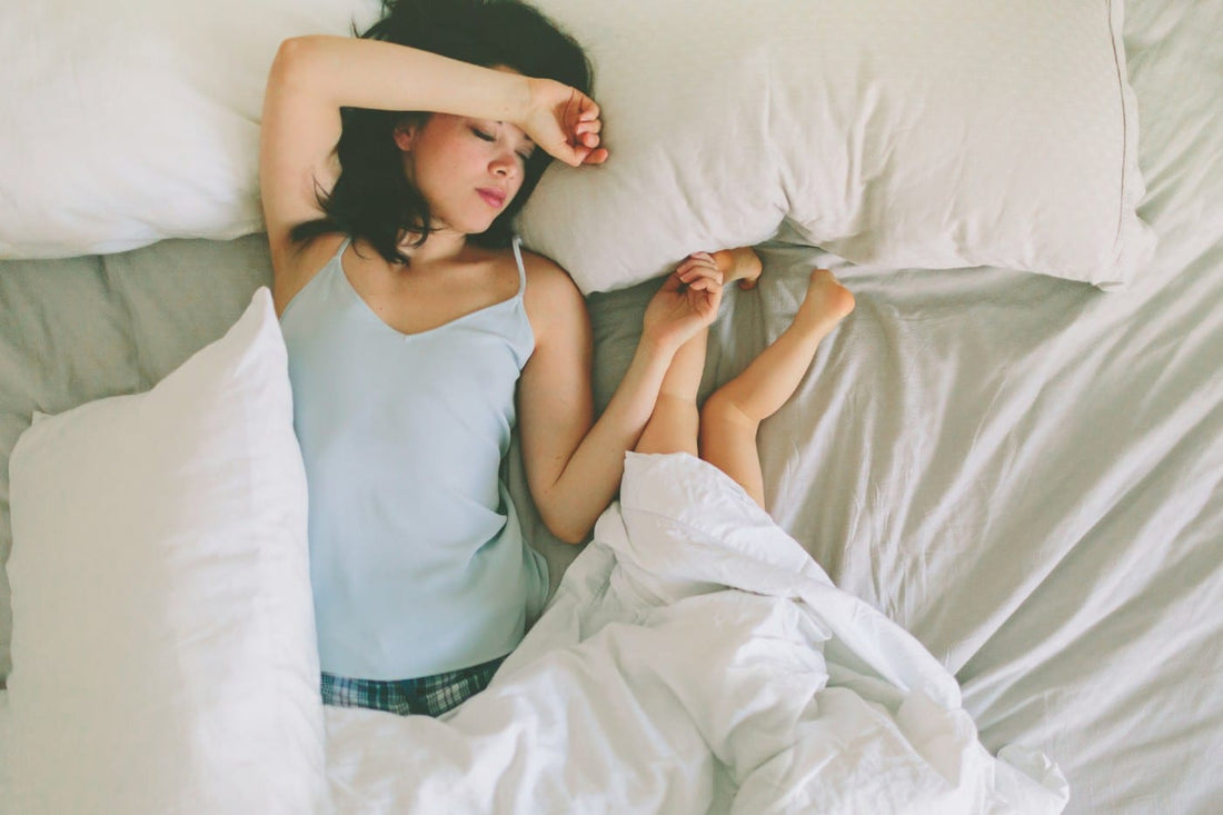 Mum bed-sharing with toddler, who is sleeping upside-down with their feet are on the pillow