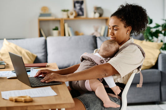 A mum works from home with a baby on her chest